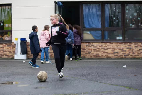 Une jeune élève en train de jouer au ballon dans la cour 